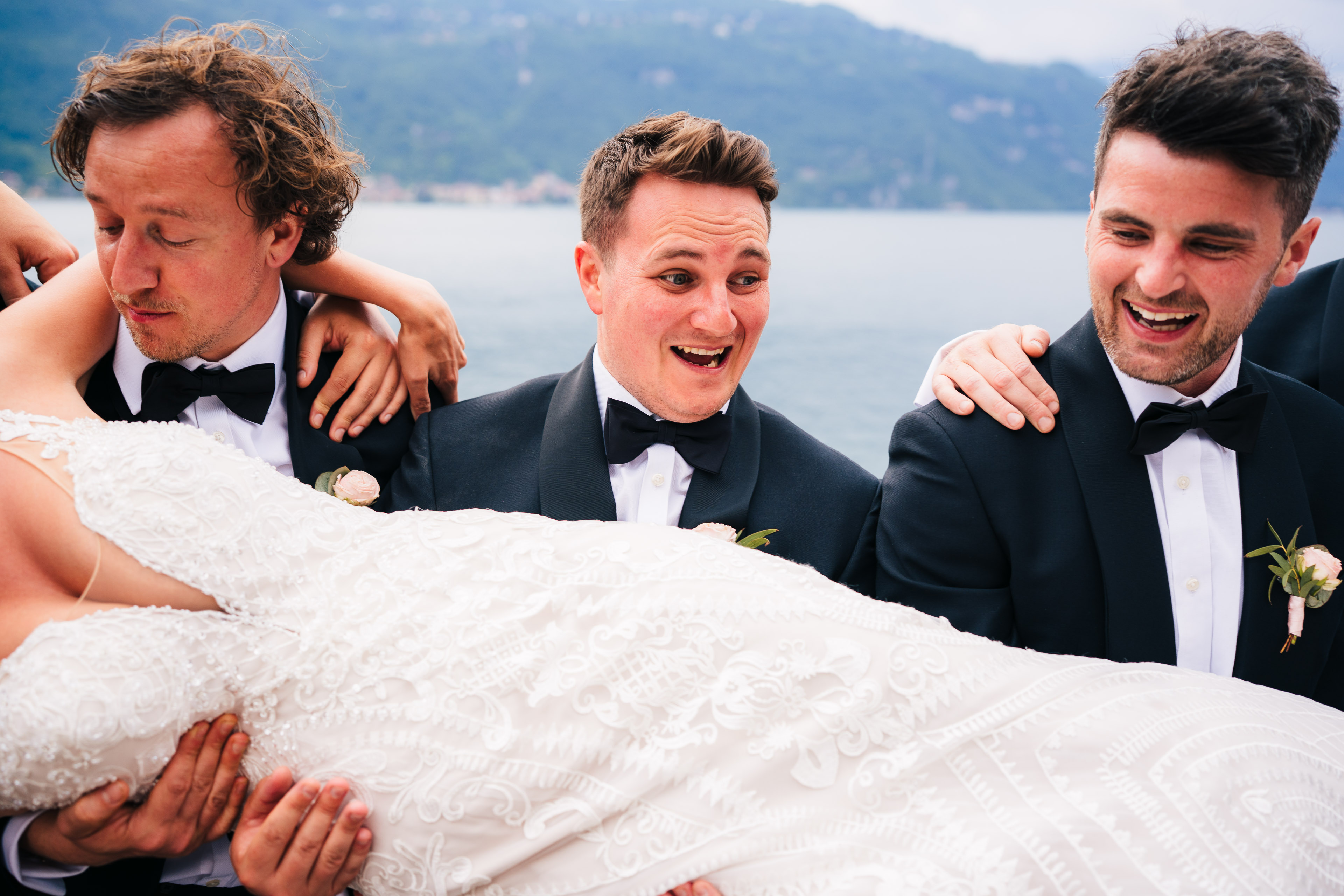 Groomsmen carrying a groom and laughing