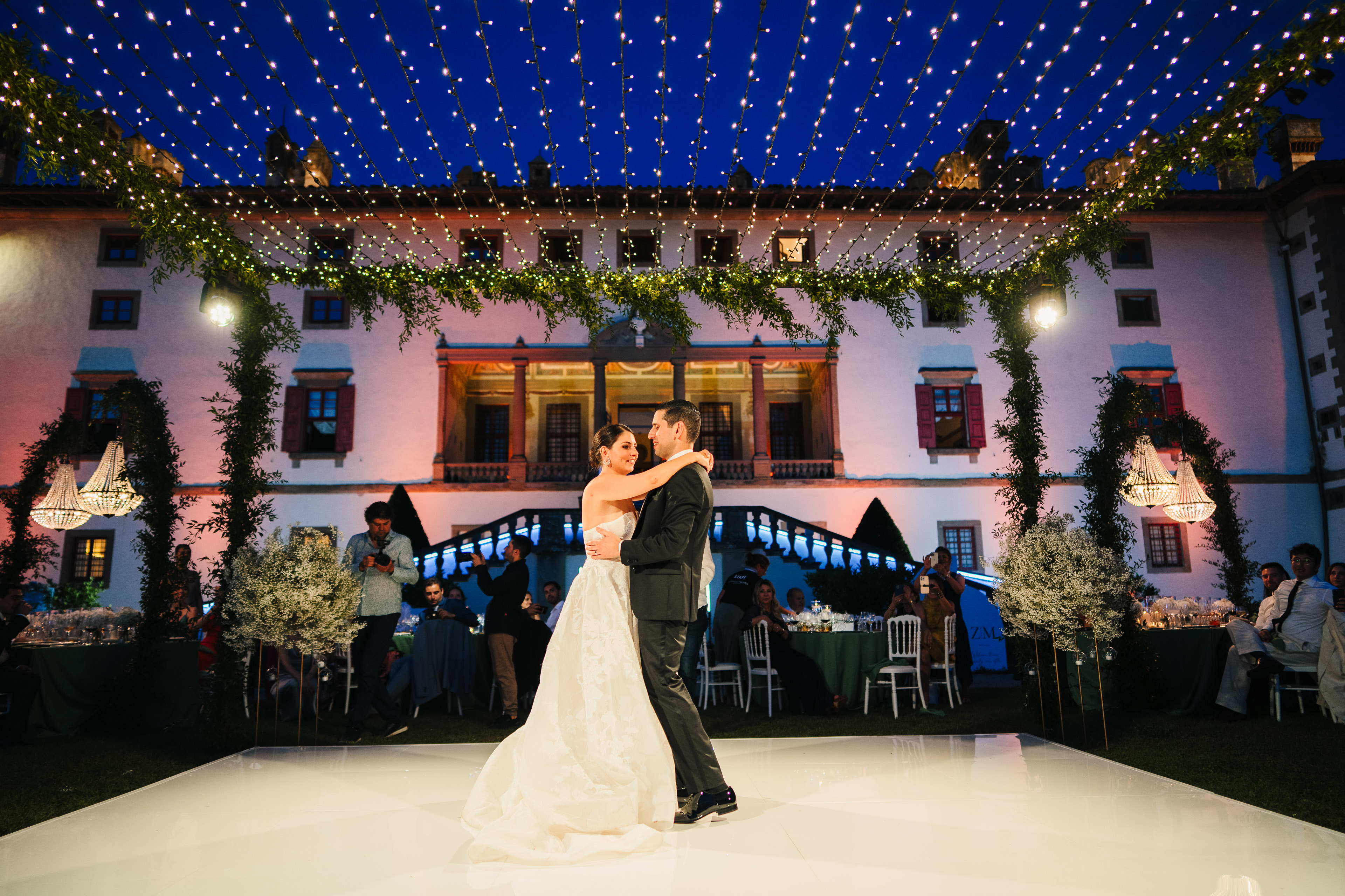 Bride and groom dancing under wedding lights at night